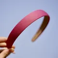 Handheld magenta fabric headband with textured finish against a clear blue sky - Solid Rose Red