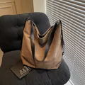 Bolso tote de lona marrón con asas de cuero negro en un sillón oscuro con estilo - café