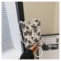 Fashionable crossbody phone bag featuring a stylish black and white cow print and metal m logo - White / One Size