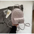 Detail of pink quilted mini backpack featuring rhinestone accents and metal chain strap - Pink