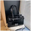 Detail of black glossy faux leather handbag featuring silver hardware and side buckle straps - One Size / Black
