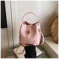 Detailed close-up of pink lychee grain leather bucket bag with golden bar lock and handles - One Size / Pink