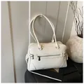 Dettaglio di una borsa tote in pelle PU color crema con cerniere e fibbie decorative - Taglia unica / Bianco
