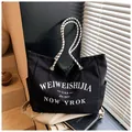 Détail du sac cabas en toile noire avec imprimé rétro et anses tissées à carreaux - Grand / Noir