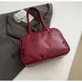 Detailed top view of a dark red faux leather Boston bag on a grey suit jacket - No Pendant / Burgundy