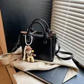 Minimalistische schwarze Leder-Eimertasche mit Lychee-Muster und geknotetem Griff - Mit Anhänger / Schwarz