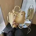 Hellgelbe Beuteltasche mit Litschi-Struktur, Doppelgriffen und niedlichem Puppenanhänger - Mit Anhänger / Gelb