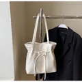 Gros plan du cabas en cuir crème avec nœud de serrage décoratif et breloques en métal - Sans Pendentif / Blanc Cassé