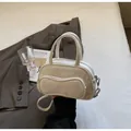 Detail der cremeweißen PU-Leder-Mini-Bowlingtasche mit einzigartiger gebogener Fronttasche - Einheitsgröße / Gebrochenes Weiß
