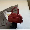 Makro-Detail einer glänzenden roten Bowlingtasche auf einem Bett mit Matisse-Buch - Einheitsgröße / Burgunderrot