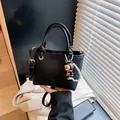 Bolso bucket negro con patrón de lichi, colgante de perlas y correa ajustable - Con Colgante / Negro