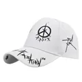 Detail of white baseball cap featuring black graffiti prints and Fashion text on the brim - White