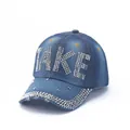 Close-up of blue denim baseball cap featuring rhinestone letters and silver cone studs - Blue TAKE