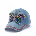 Close-up of a blue denim baseball cap featuring a large colorful rhinestone butterfly detail - Light Blue Heavy Beaded Butterfly