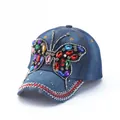 Detail of blue denim baseball cap featuring colorful rhinestone butterfly and studded brim - Blue Heavy Beaded Butterfly