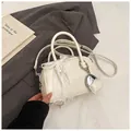 Close-up of cream leather handbag with lace bow detail and heart pendant on a stylish background - With Pendant / White