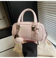 Close-up of pink patent leather boston bag with heart charm and silver hardware - With Pendant / Pink With Pendant