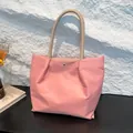 Borsa tote in nylon rosa con manici marroni e chiusura magnetica su tavolo scuro - Rosa