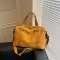 Ginger yellow travel tote bag in durable nylon with adjustable shoulder strap on leather sofa - Brown