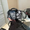 Elegante borsa a mano con motivo a serpente bianco e nero, borchie argento e manici neri - Nero