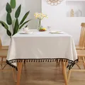 Mantel minimalista de lino crema con borlas negras sobre mesa de comedor de madera - 140x250CM / Blanco con borlas negras