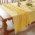 Detailed view of bright yellow cotton tablecloth draped over a wooden dining table - Light Yellow
