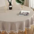 Detail van beige rond linnen tafelkleed met witte franjes op een houten tafel - Khaki