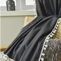 Detail of dark grey blanket with white pom-pom trim draped on a beige woven chair - Extra Long Style / Dark Gray (Hook Style)