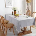 Nappe rectangulaire minimaliste en lin bleu clair avec pompons blancs sur table en bois - Gris