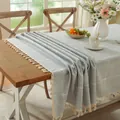 Dettaglio della tovaglia a quadretti azzurra con nappe bianche in un ambiente rustico - 140*140cm / Griglia grigia ricamata (motivo completo) con nappine