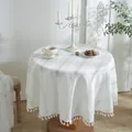 Primer plano de mantel redondo blanco con textura jacquard de rayas y elegantes borlas de flecos - Diámetro 140 / Blanco Trenzado