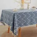 Nappe à motif de vagues bleu et beige avec des pompons décoratifs sur une table en bois - Rond 120cm / Vague Bleue Jacquard + Glands