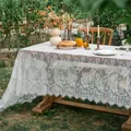 Detailed view of white floral lace tablecloth with elegant scalloped edges on outdoor table - New Lace Floral