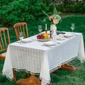 White boho lace tablecloth with pompom fringe on a rectangle table in a green garden - 60x60 / White Clover Pattern (White Tassel)