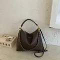 Close-up of dark brown lychee texture leather hobo bag with gold hardware and woven chain - Brown
