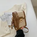 Beige quilted crossbody phone bag with brown trim and golden lock detail in hand - White and Brown