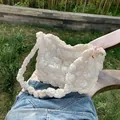Chic beige ruched cloud tote bag with puffy texture and pink charm on a park bench - White