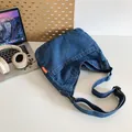 Dunkelblaue Denim Umhängetasche mit orangefarbenem Etikett auf Schreibtisch - Dunkelblau
