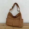Braune Canvas-Umhängetasche mit großen Klappentaschen auf einem Tisch aus Naturholz - Braun