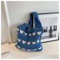 Nahaufnahme der blauen Stricktasche mit weißem Herzmuster und Zopfstrick-Textur-Details - Blau und Aprikose