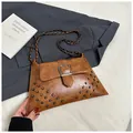 Macro detail of brown leather crossbody bag featuring metal rivets and chain strap - Brown
