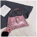 Close-up of pink retro crossbody bag with silver buckles, studs and metallic chain strap - Pink