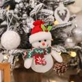 Simpatico pupazzo di neve di Natale in maglia appeso a un albero innevato festoso - Pupazzo di neve