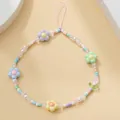 Gros plan de la dragonne de téléphone en perles macaron avec fleurs 3D et tulipe - Lanière en Cristal Fleur à Cinq Pétales Feuille Verte