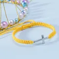 Dettaglio del bracciale in corda gialla intrecciata con croce d'argento su sfondo blu - Giallo