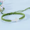 Dettaglio del bracciale intrecciato a mano verde erba con croce in metallo argento e laccio - verde-grigio