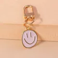 Pink enamel smiley face charm with gold-plated D-ring keychain on beige pedestal - Pink