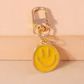 Macro shot of gold-plated smiley face pendant with yellow enamel detail and D-ring buckle - Yellow