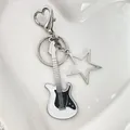 Macro detail of silver guitar keychain with black enamel on a white heart ceramic plate - Hollow Star White Guitar Keychain