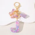 Macro shot of resin letter J keychain with pink heart glitter and purple tassel - Letter J Purple Tassel